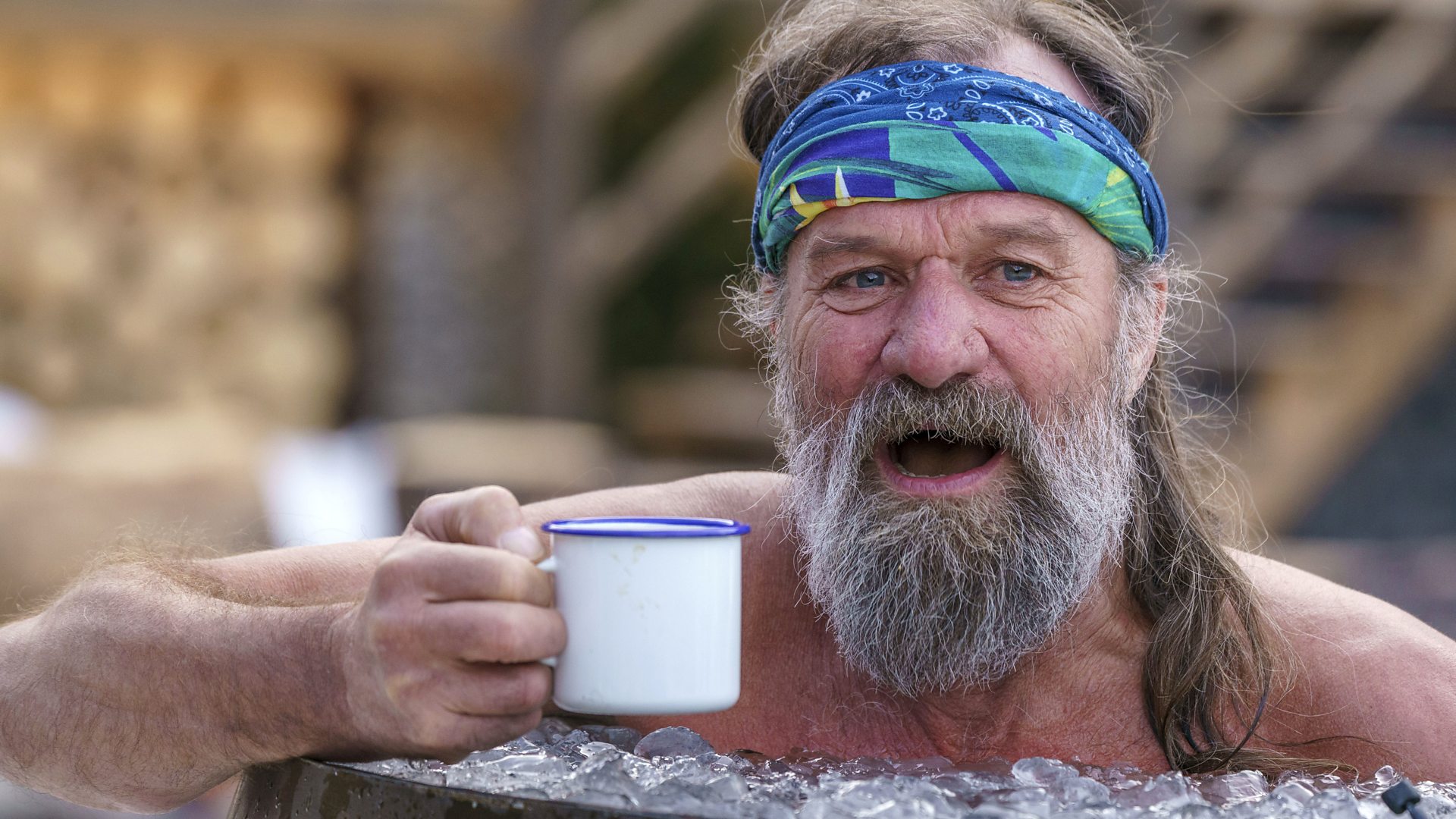 Wim Hof holding a mug in an ice bath